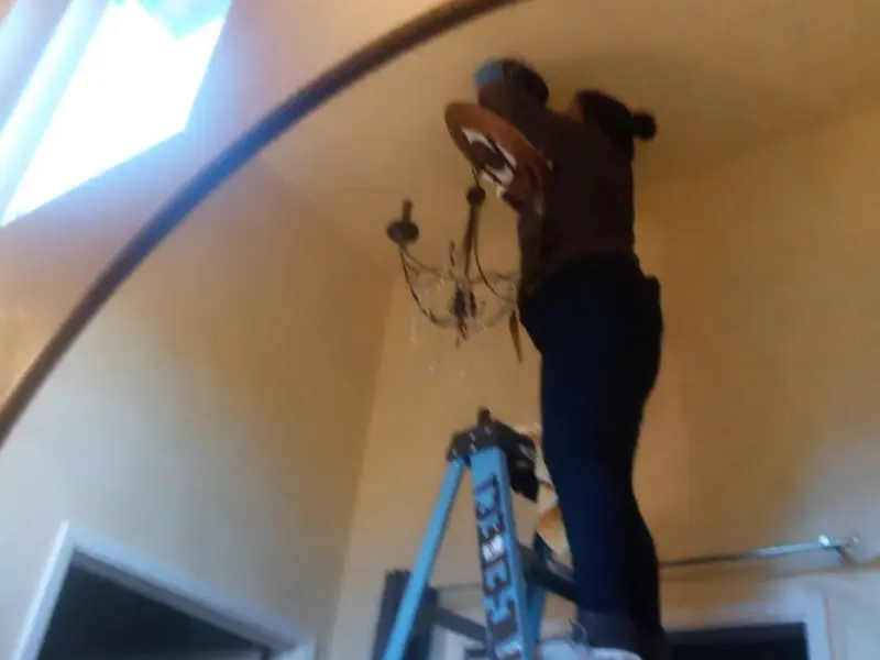 Electrician installing a chandelier in a Brookhaven residence
